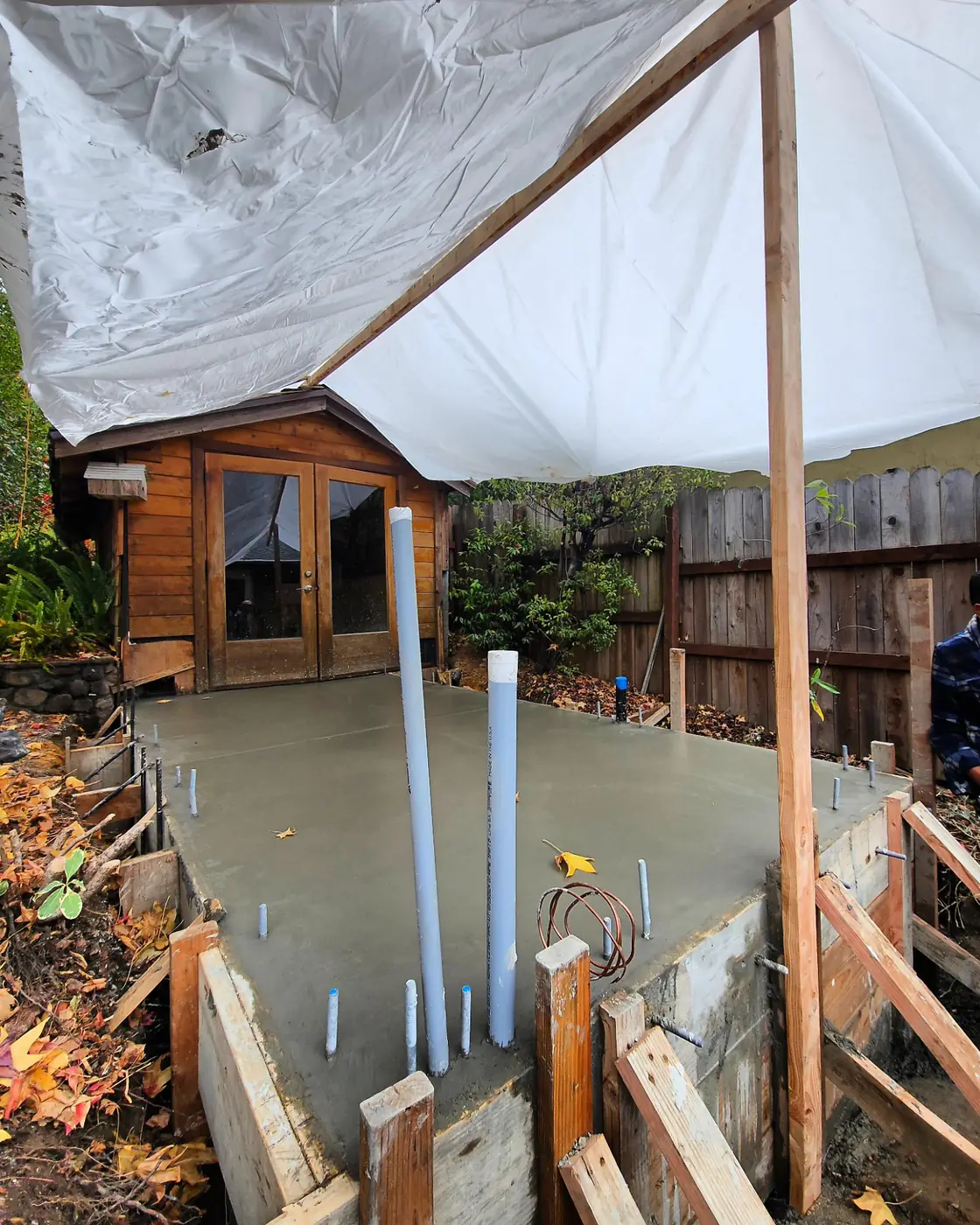 Poured slab under rain tarp — Backyard ADU Foundation, SF Bay Area
