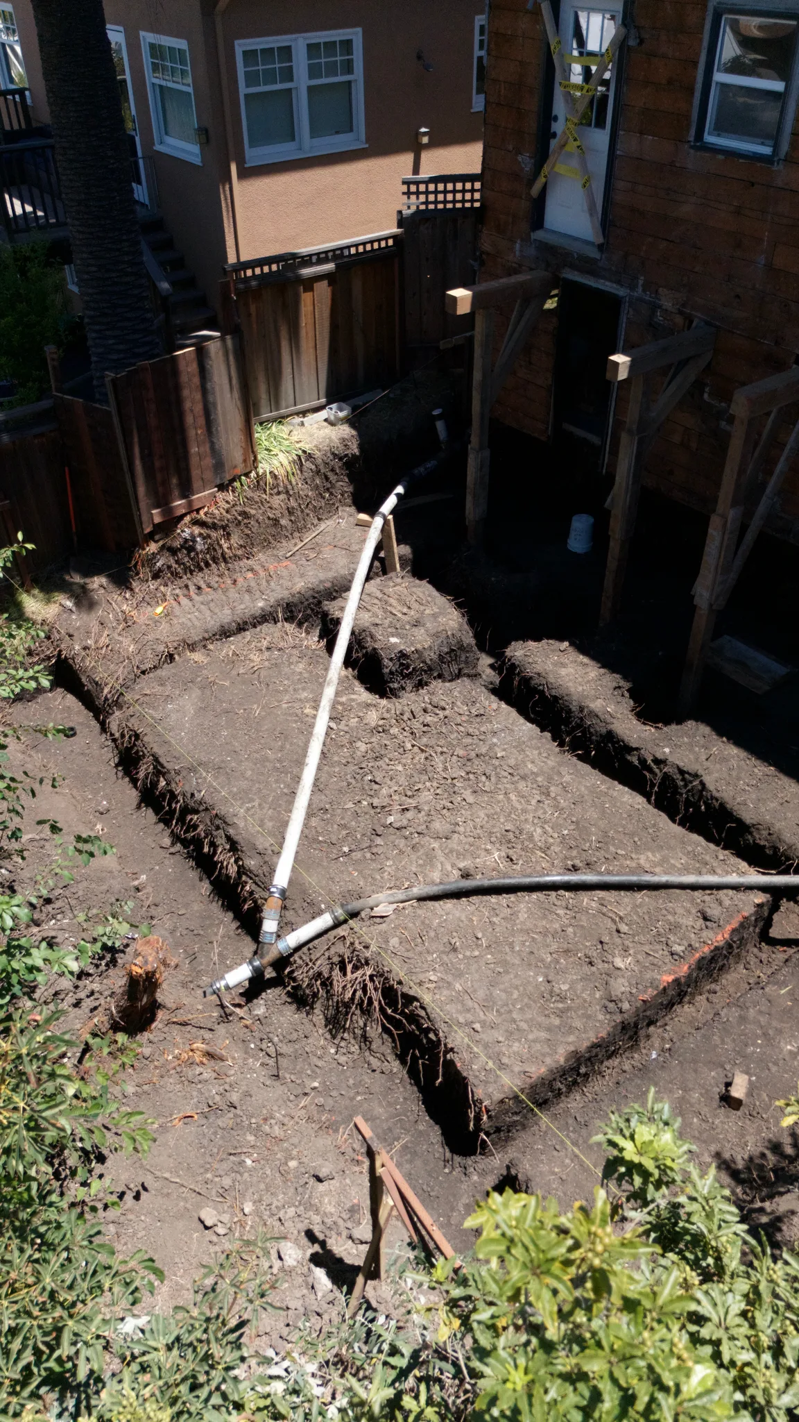 Footing and grade-beam trenches cut behind the shored rear wall of the home — Albany Home Addition Foundation, Albany, CA