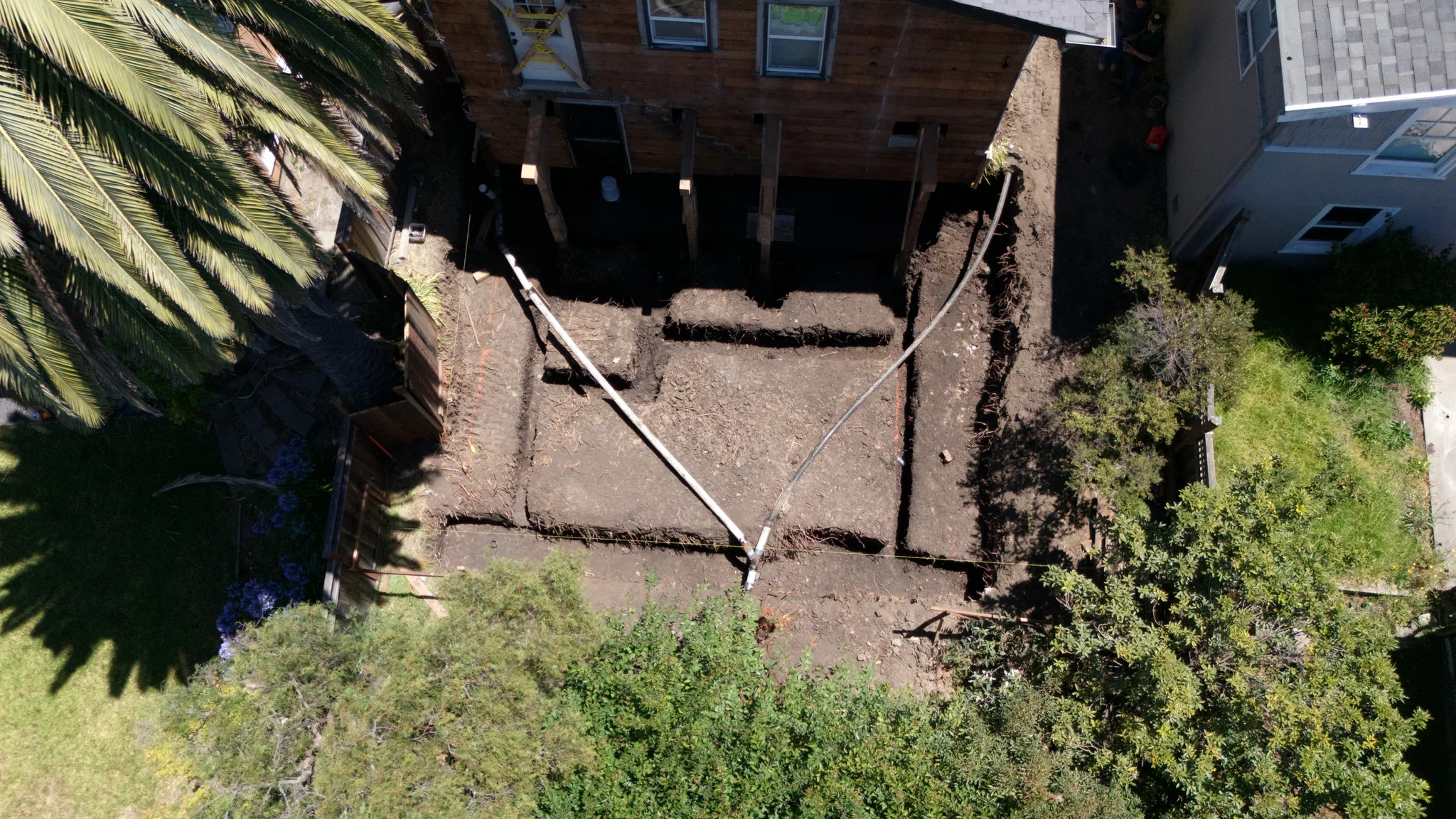 Aerial of the excavated addition footprint, the house carried on temporary posts above — Albany Home Addition Foundation, Albany, CA