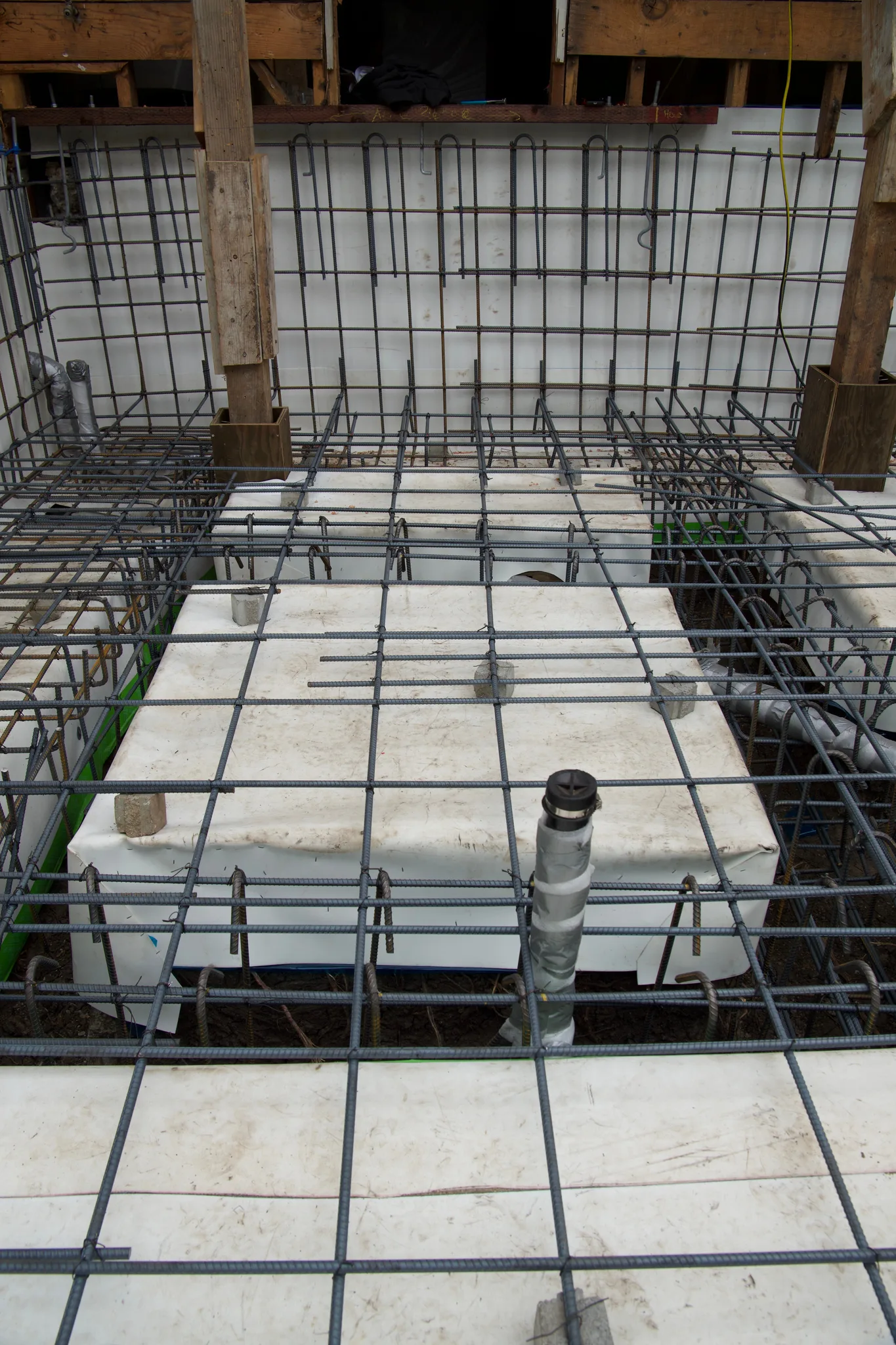 Void forms and wall steel meeting the shored rear wall of the house — Albany Home Addition Foundation, Albany, CA