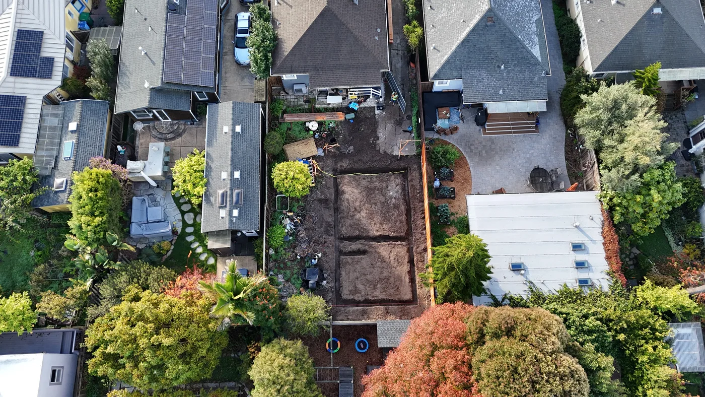 Aerial of the backyard with the ADU footprint excavated, existing homes packed in on both sides — Berkeley Backyard Detached ADU, Berkeley, CA