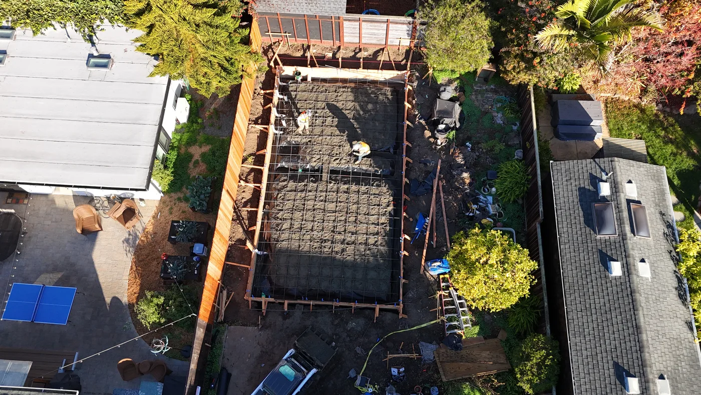 Formed slab with the two-way rebar mat tied out, crew working across the pad — Berkeley Backyard Detached ADU, Berkeley, CA