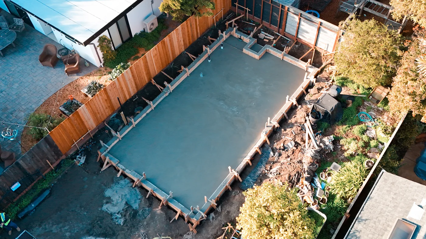The finished slab and short stem wall from above, new redwood fence running along the property line — Berkeley Backyard Detached ADU, Berkeley, CA