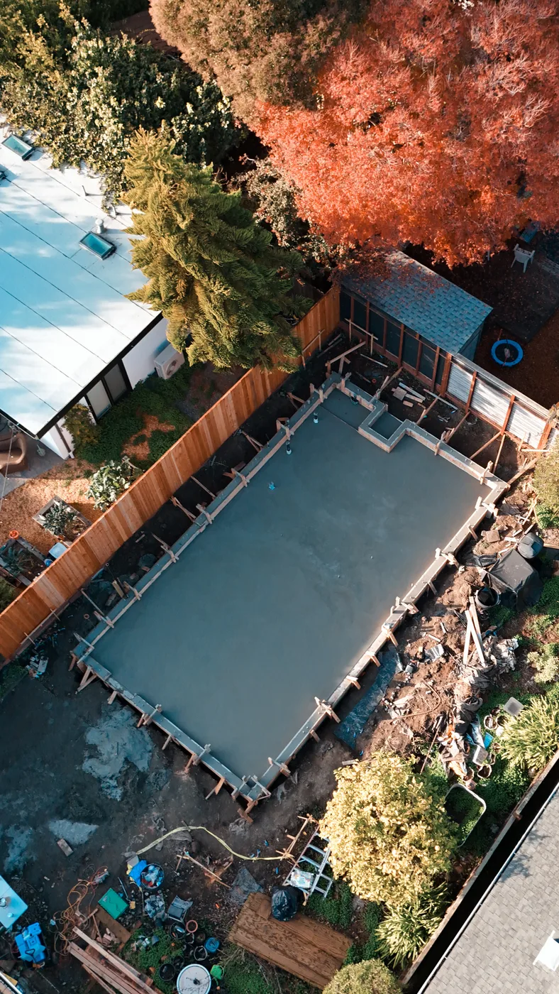 The completed slab in the backyard, fall foliage and neighboring rooflines all around it — Berkeley Backyard Detached ADU, Berkeley, CA
