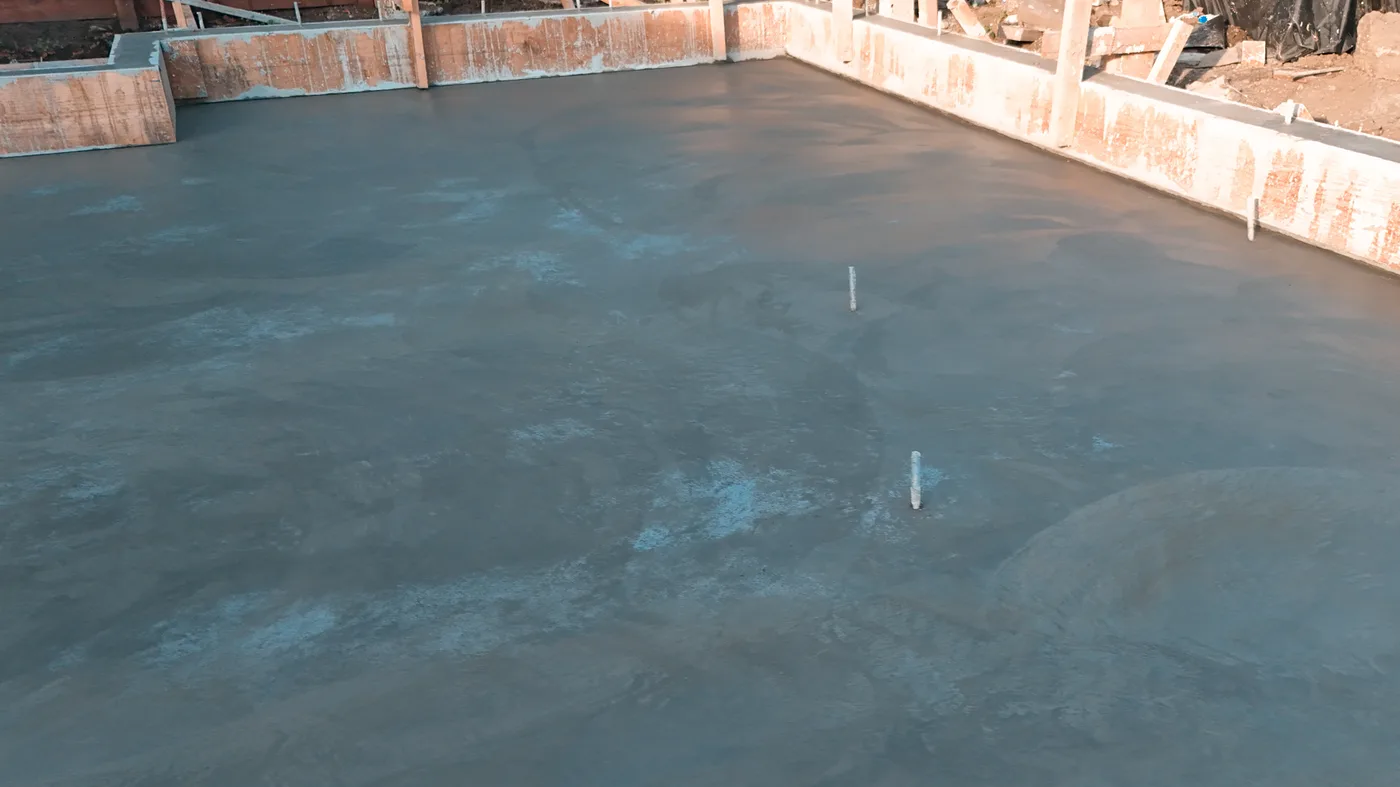 Ground-level view across the freshly steel-troweled slab with plumbing stub-ups and the form boards still in place — Berkeley Backyard Detached ADU, Berkeley, CA