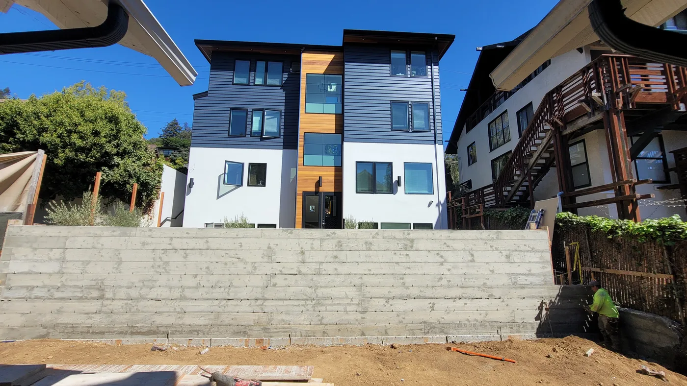 Completed board-formed retaining wall below the finished student-housing building in Berkeley