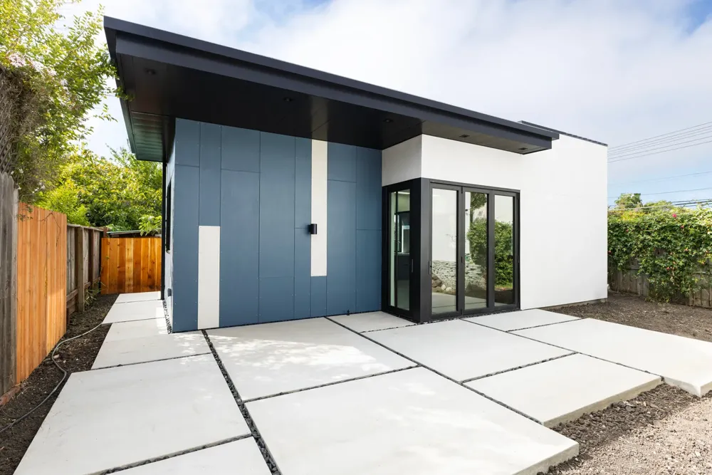 Finished ADU with blue panel siding and a poured concrete paver patio — 6516 Potrero, Burton Builders