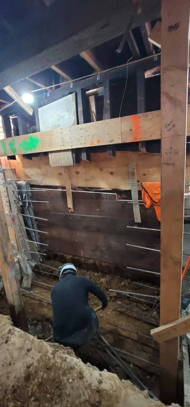 Crew member digging along the shored perimeter wall with soldier piles and lagging — Durant Basement Foundation, Berkeley, CA