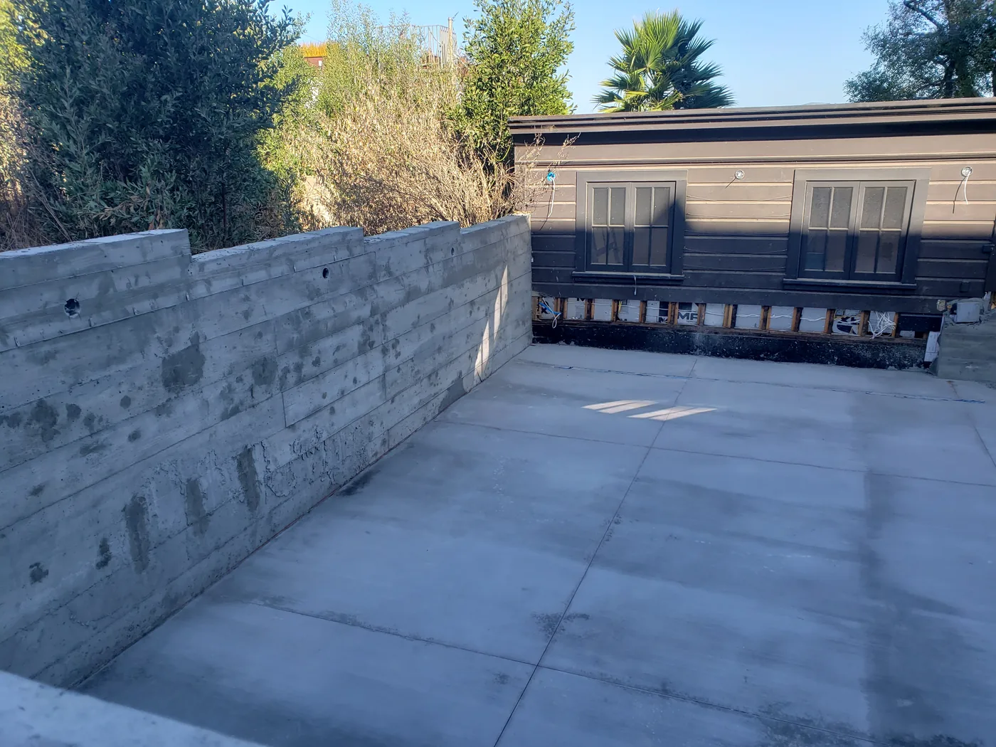 Completed court slab and board-formed retaining wall, estate house alongside — Lombard Street Basketball Court Foundation, San Francisco, CA