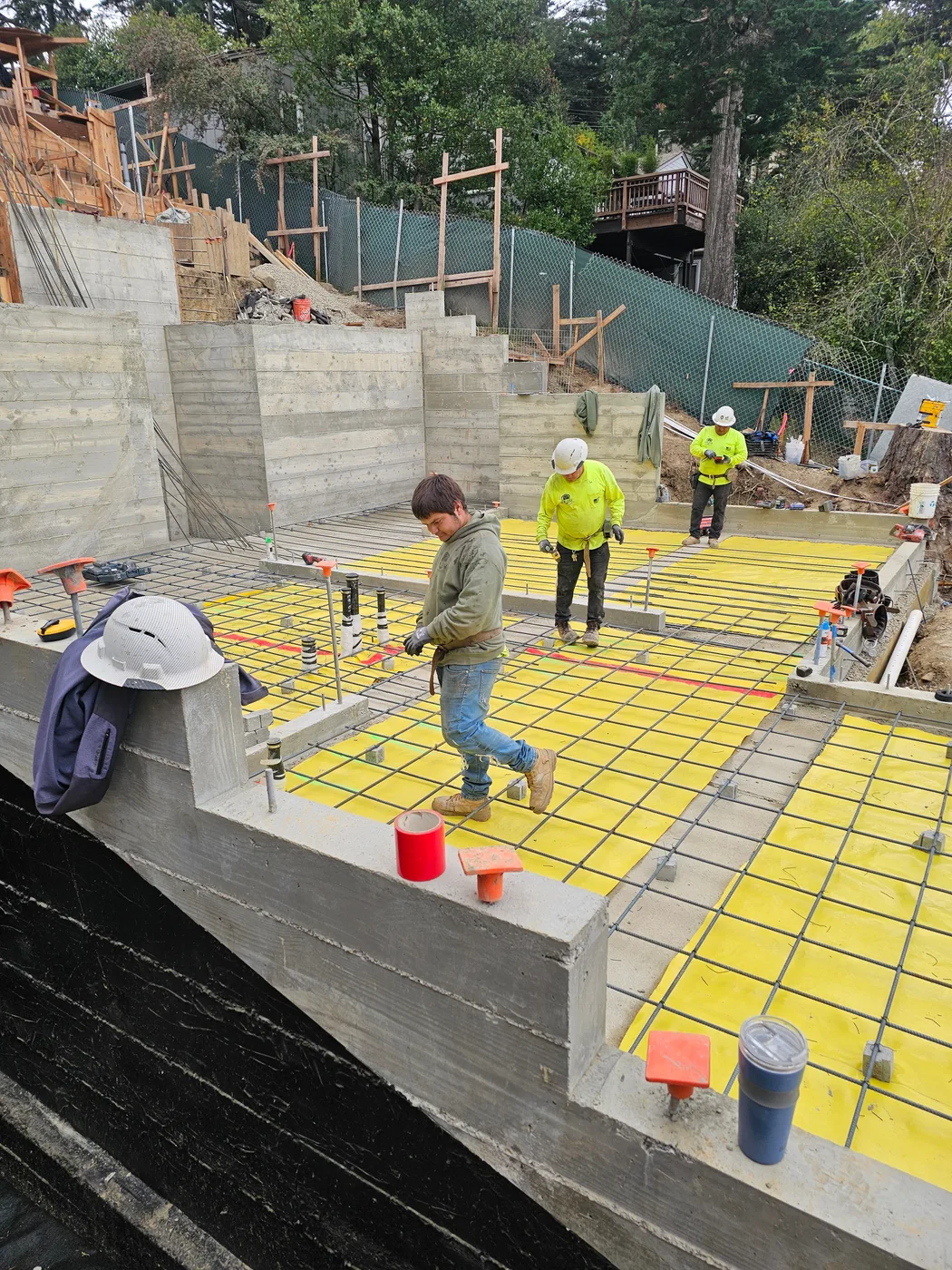 Worker on the mat-slab rebar and insulation grid before the pour — Oakland Hills Custom Home, Oakland, CA