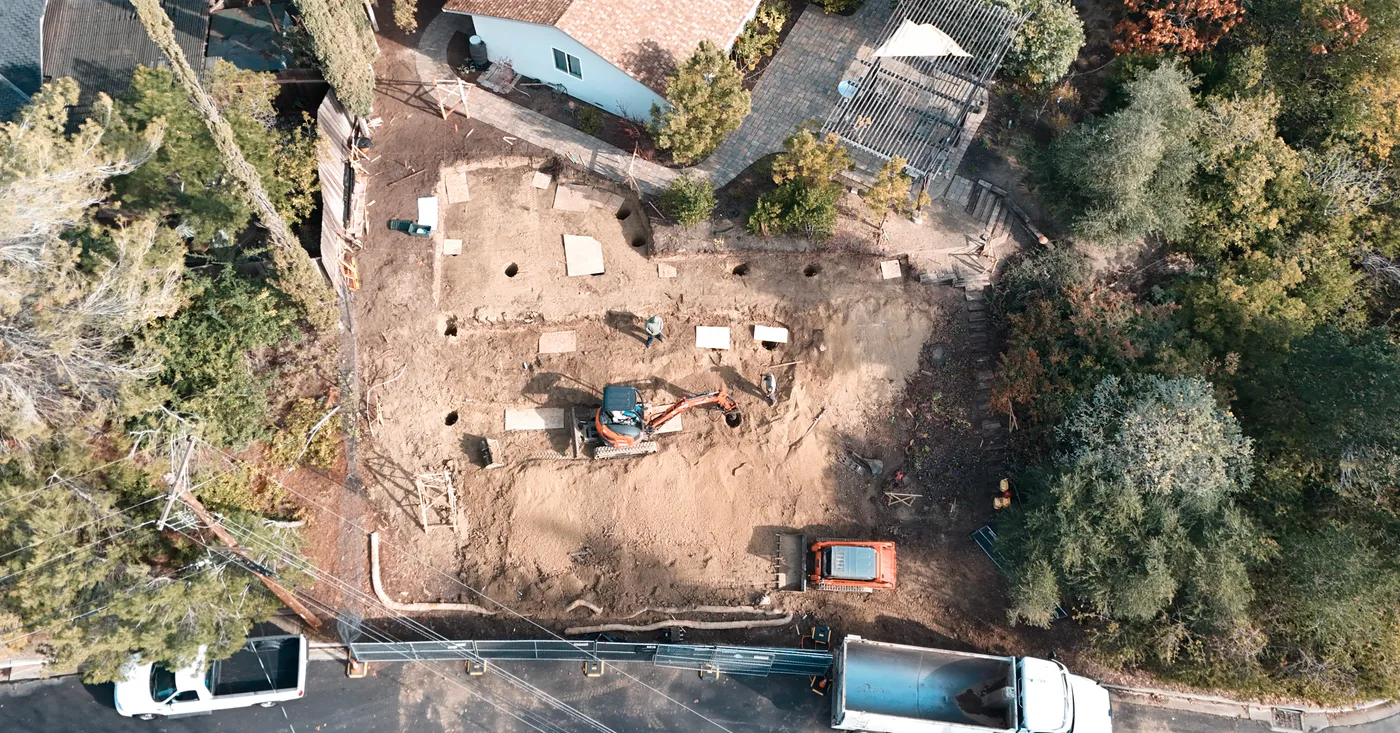 Top-down aerial of the excavated pad with the haul truck staged at the curb — Steep Hillside Lafayette ADU, Lafayette, CA