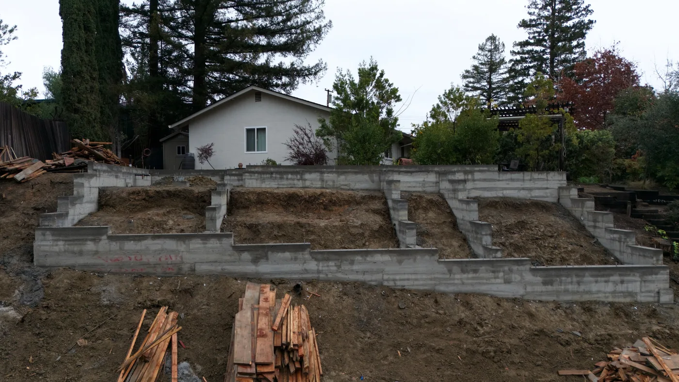 Elevation view of the tiered stem walls with the existing house behind — Steep Hillside Lafayette ADU, Lafayette, CA